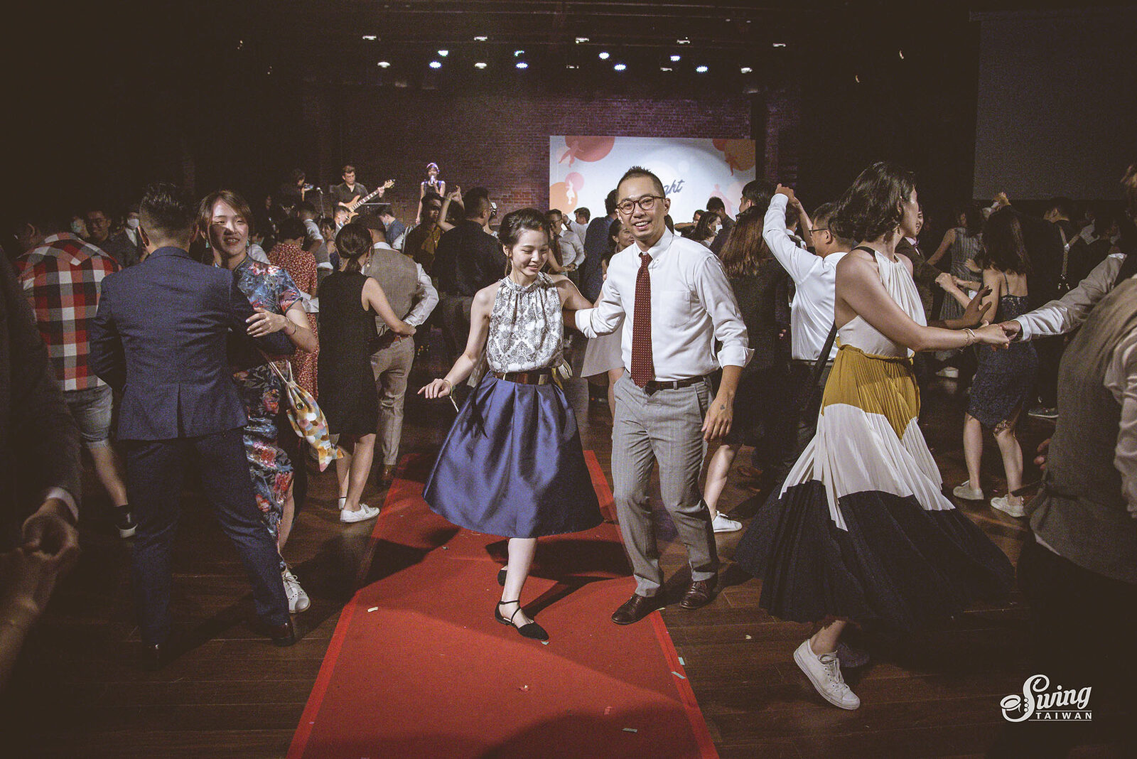 社交舞會現場，多對舞者在紅地毯舞池上一起跳搖擺舞